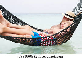 Grandfather And Grandson Relaxing In Beach Hammock 