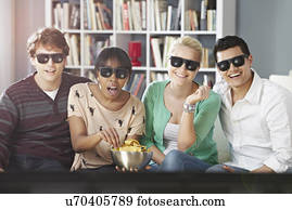 Young people watching 3D television, wearing 3D glasses