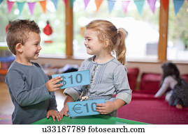 Boy and girl counting euro currency at nursery school