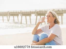Senior woman drinking water on beach