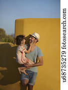 Father holding daughter, leaning against wall, Costa Brava, Catalonia, Spain