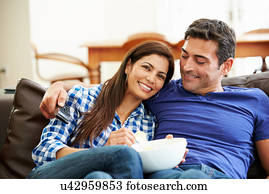 Couple Sitting On Sofa Watching TV Together