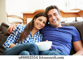 Couple Sitting On Sofa Watching TV Together