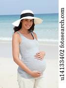 Portrait of pregnant mid adult woman wearing sunhat on beach