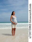 Pregnant mid adult woman standing with eyes closed in sea