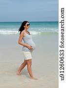 Pregnant mid adult woman strolling on beach