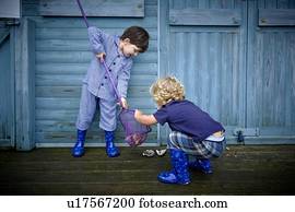 MODEL RELEASED. Two boys playing in front of beach hut with fishing net.