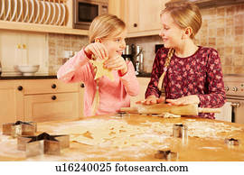 Two girls baking star shape pastry at kitchen table