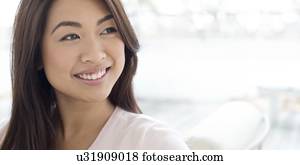 Woman with brown hair smiling and looking away