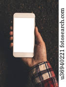 Farmer holding smartphone over soil