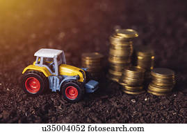 Toy tractor with stacked coins, conceptual image