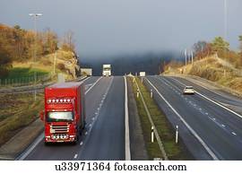 Trucks on a highway in the early morning with mist in the background.