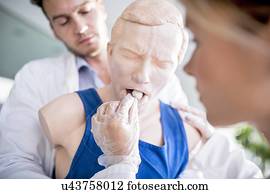 Doctor practising the Heimlich manoeuvre on a training dummy.