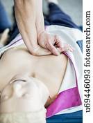 First-aider practising chest compressions on a CPR training dummy.