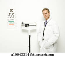 Mid-adult Caucasian male doctor standing next to scale with eye chart on wall.