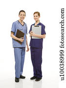 Portrait of Caucasian women doctors in medical scrubs standing holding medical charts against white background.
