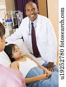 Doctor Standing In Hospital Room With Patient