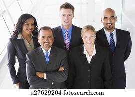 Group of co-workers standing in office space smiling (high key)