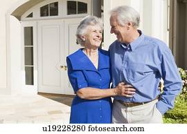 Senior couple standing outside their home