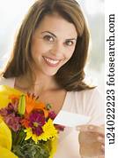 Woman holding flowers and note smiling