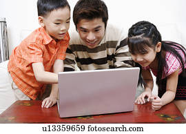 Mid adult man using a laptop with his son and daughter beside him
