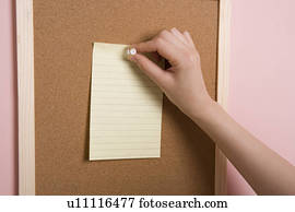 Woman's hand pinning memo to bulletin board Woman's hand pinning memo to bulletin board
