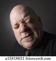 Bald man squinting and making facial expression