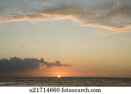 Sun rising over horizon of ocean