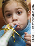 Caucasian girl blowing noisemaker and making facial expression.