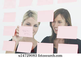 Women writing notes on glass wall Women writing notes on glass wall