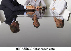Three business people's reflection in a table. Three business people's reflection in a table.