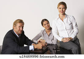 Three businesspeople at a table smiling.
