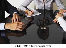 Three businesspeople with reflections at a table working. Three businesspeople with reflections at a table working.