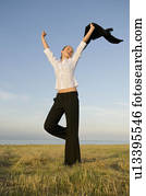 Business woman in a field with arms up