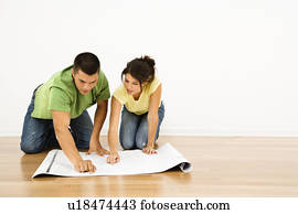 Attractive young adult couple looking at house plans.