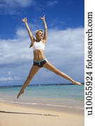 Caucasian young adult woman jumping on beach.