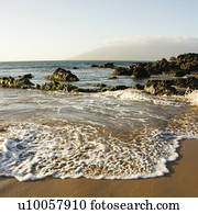 Landscape of waves lapping on rocky beach.