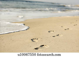 Scenic sandy coastline with footprints and waves.