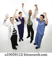 Full-length portrait of African-American man and Caucasian women medical healthcare workers in uniforms cheering with arms raised standing against white background.