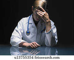 Portrait of concerned female doctor at her desk working late head in hand. Portrait of concerned female doctor at her desk working late head in hand.