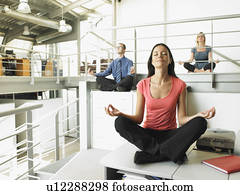 Young adults sitting on office desks in a yoga position