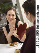 Man giving a heart shaped box of chocolates to woman 