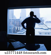 Male on phone in office with skyline in background