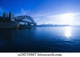 View of Sydney Harbour with Sydney Harbour bridge and distant skyline at dusk in Sydney, Australia.