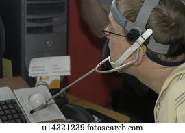 Man with significant disabilities using headgear to operate communications apparatus. Man with significant disabilities using headgear to operate communications apparatus.
