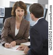 Businesswoman and businessman discussing paperwork