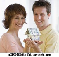 Couple holding house made of money