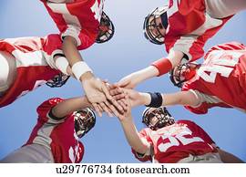 Football players joining hands in huddle