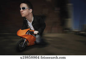 Bizarre image of man riding on a mini motorcycle