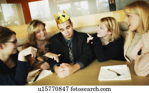 Man with flimsy crown on head and women paying attention to him